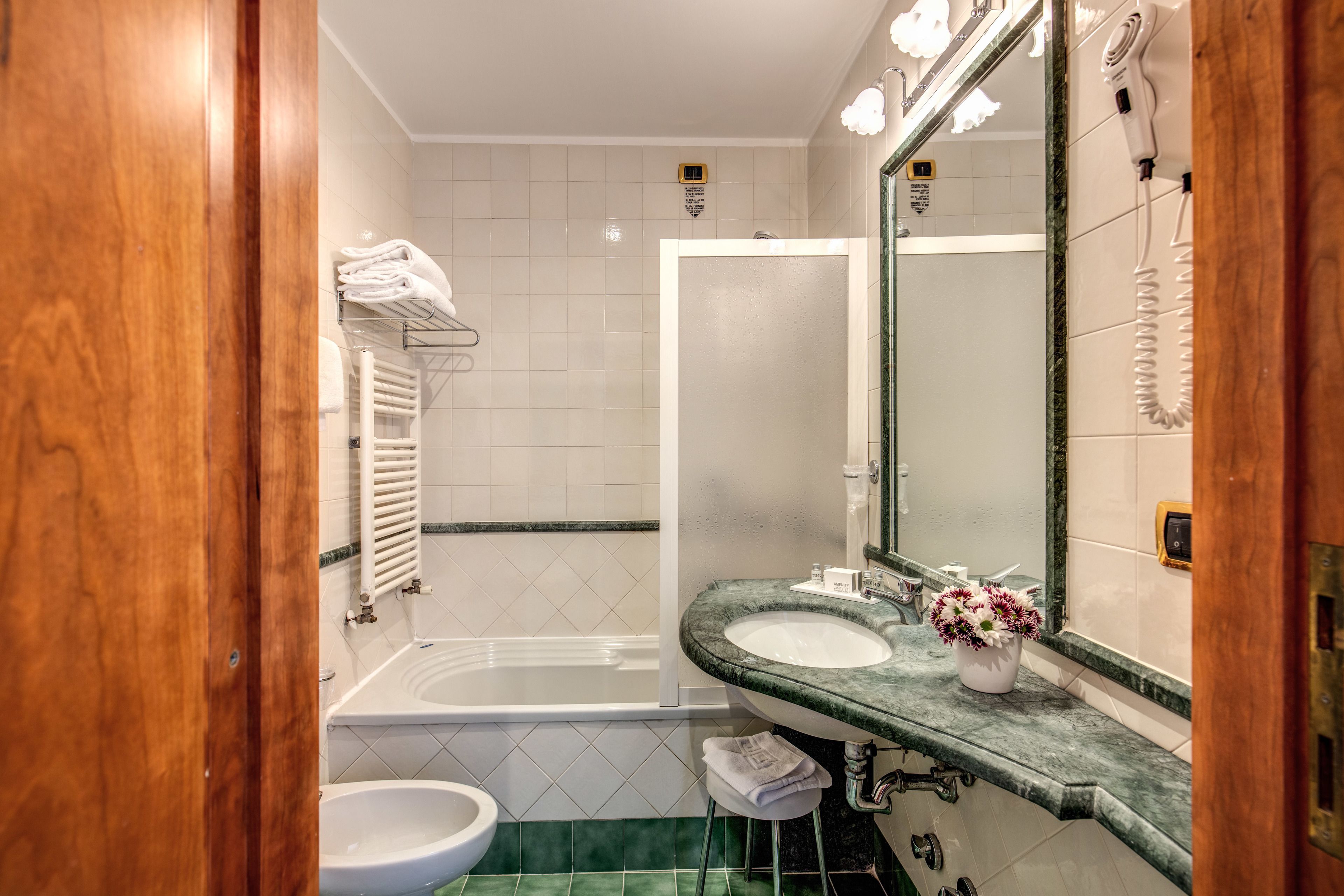 A bathroom with a bathtub, a sink, a mirror, and a towel rack.