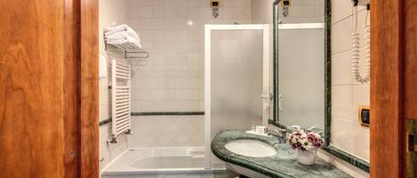 A bathroom with a bathtub, a sink, a mirror, and a towel rack.