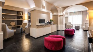 A modern lobby with a reception desk, seating area, and a large clock on the wall. - Hotel Villafranca (Rome)