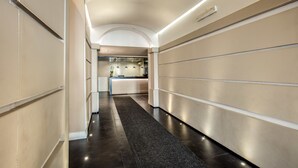 A modern hotel corridor with a reception desk, a dark carpet, and a minimalist design. - Hotel Villafranca (Rome)