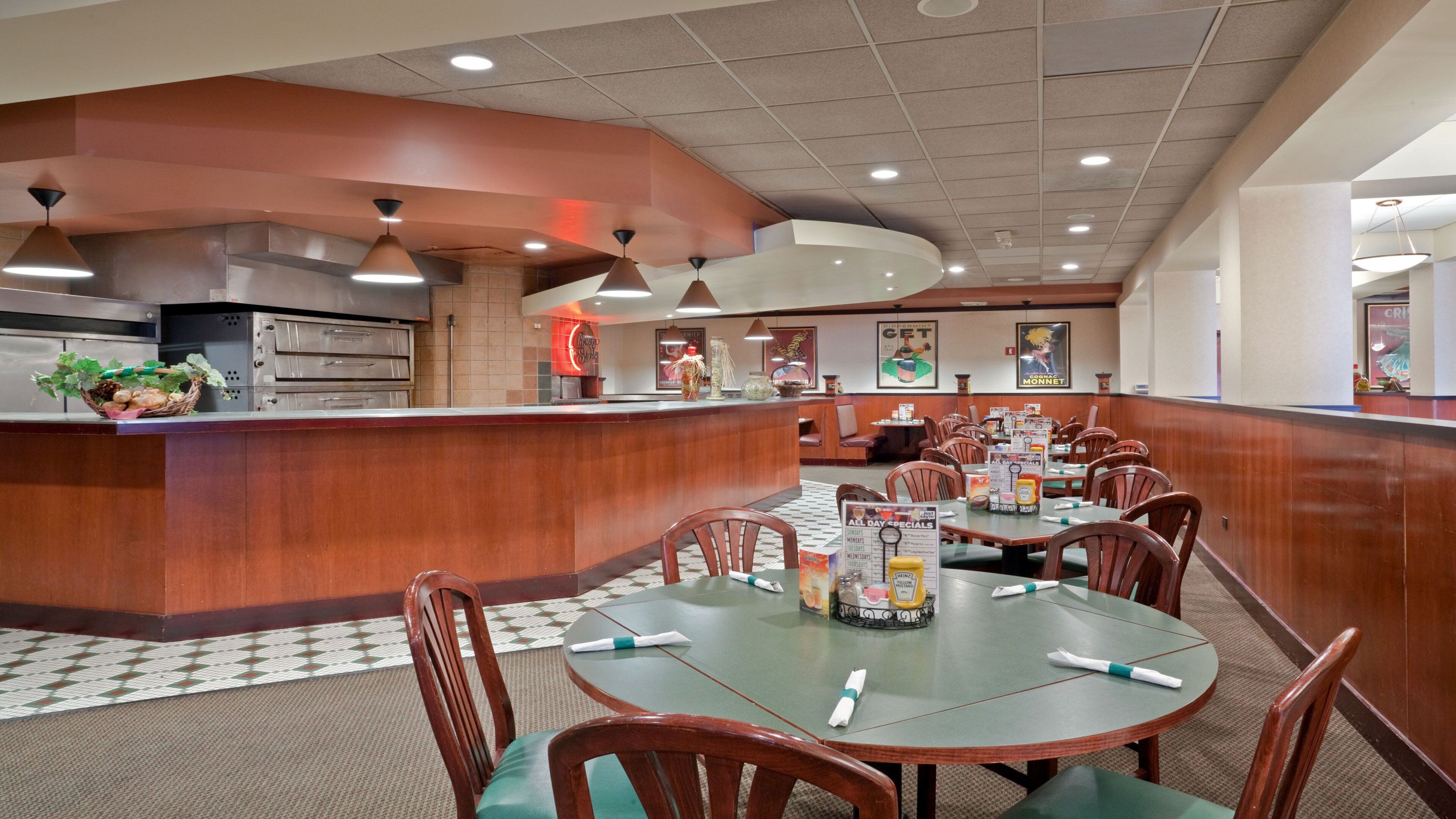 A restaurant interior with a counter, dining tables, chairs, and a menu stand.