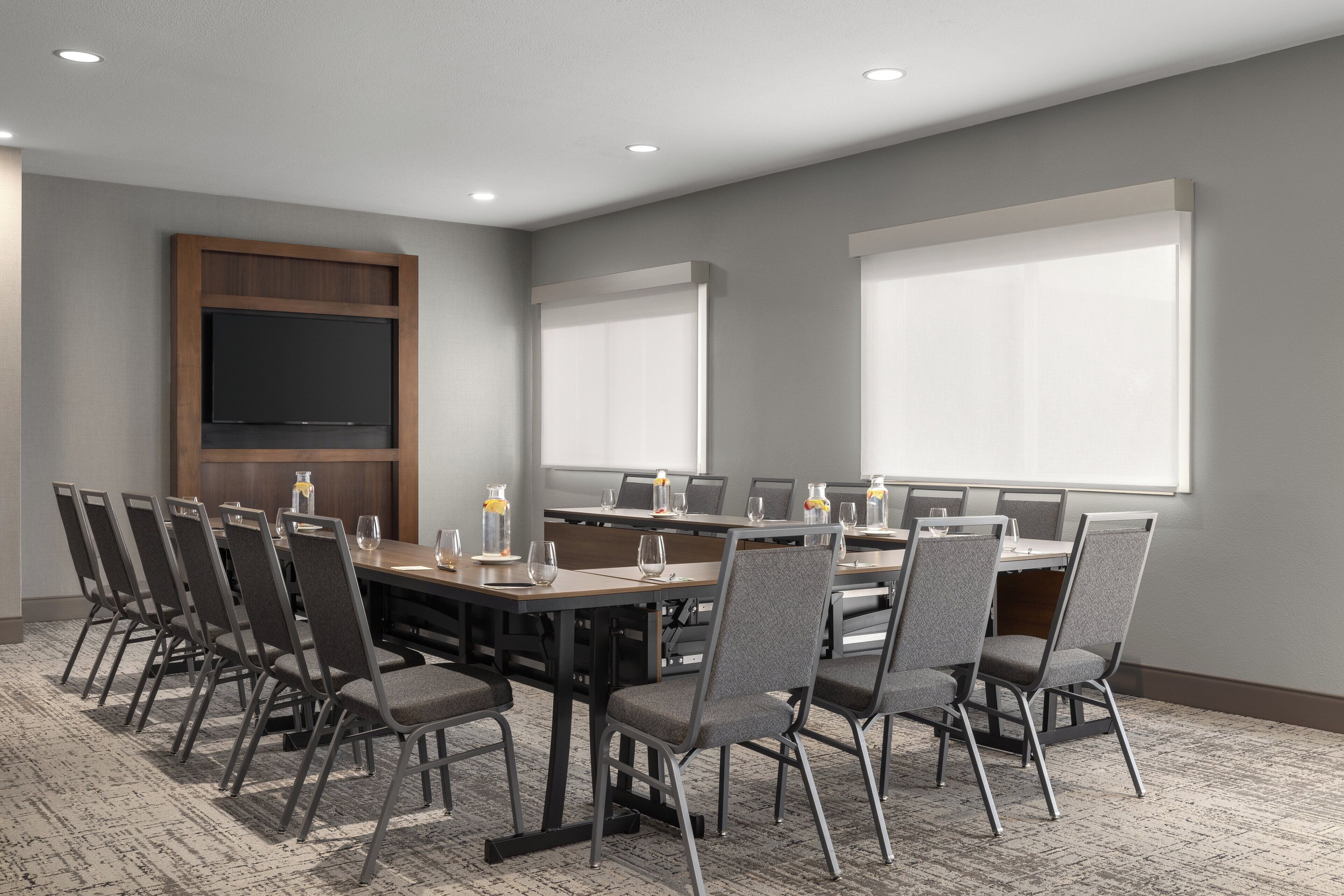 A conference room with a long table, chairs, and a flat-screen TV.