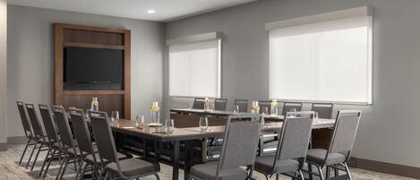 A conference room with a long table, chairs, and a flat-screen TV.