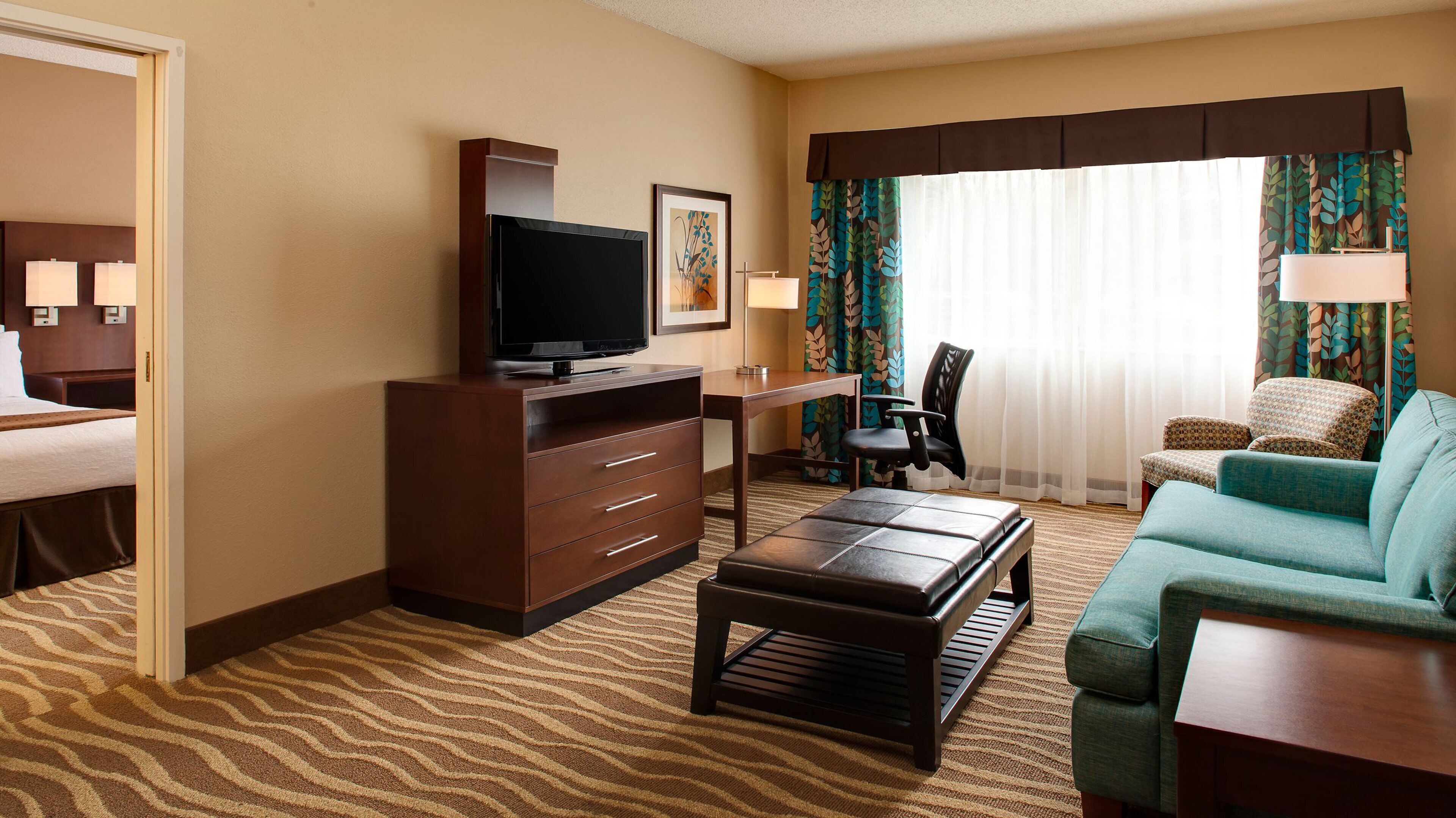 Une chambre d’hôtel comprenant un lit, un bureau avec une télévision, un canapé et un fauteuil.