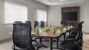 A conference room with a long table, chairs, and a large screen. - Holiday Inn & Suites Overland Park West by IHG (Lenexa)