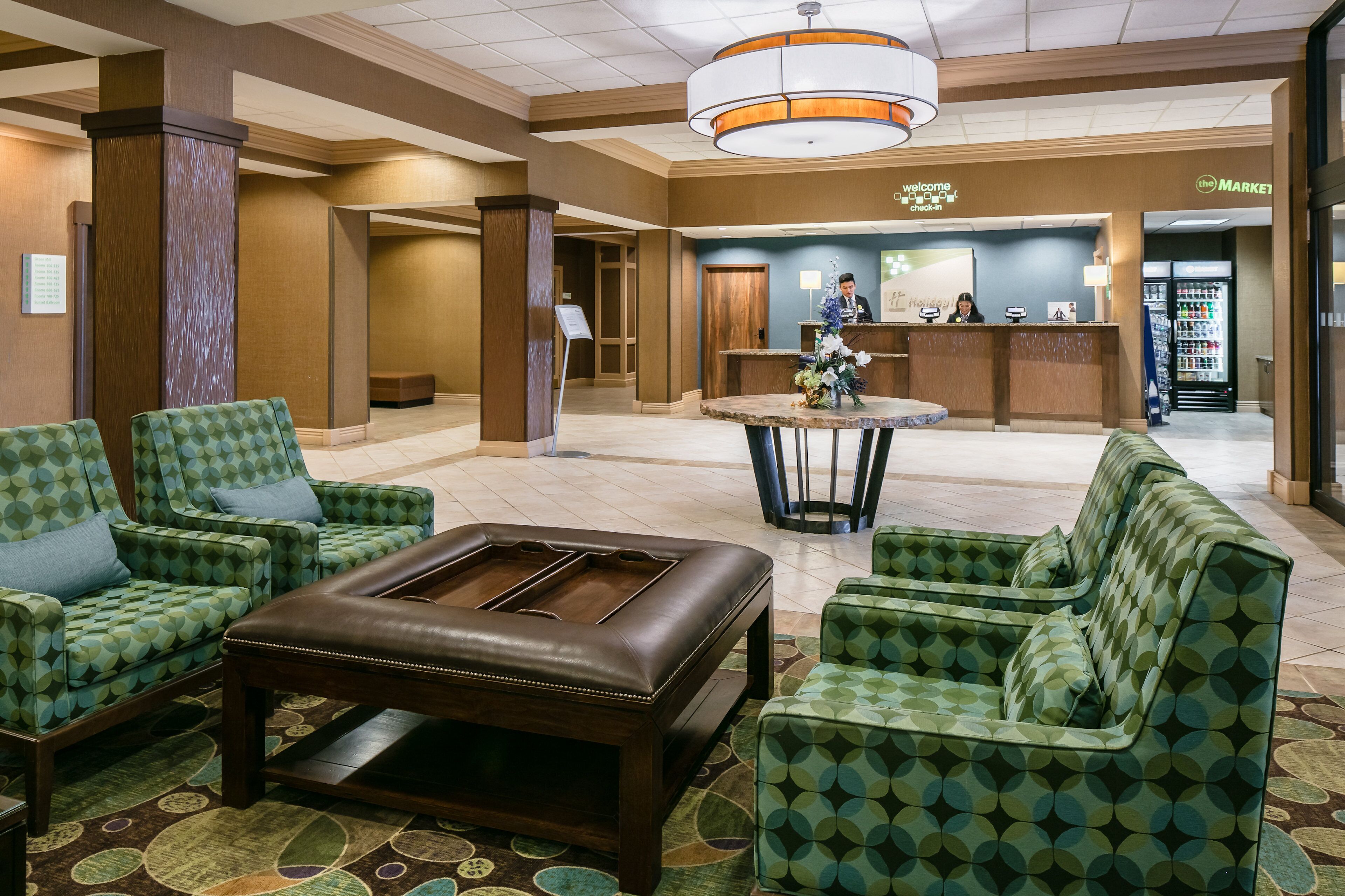 A lobby with a reception desk, seating area, and a vending machine.