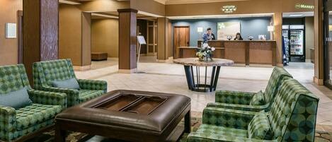 A lobby with a reception desk, seating area, and a vending machine.