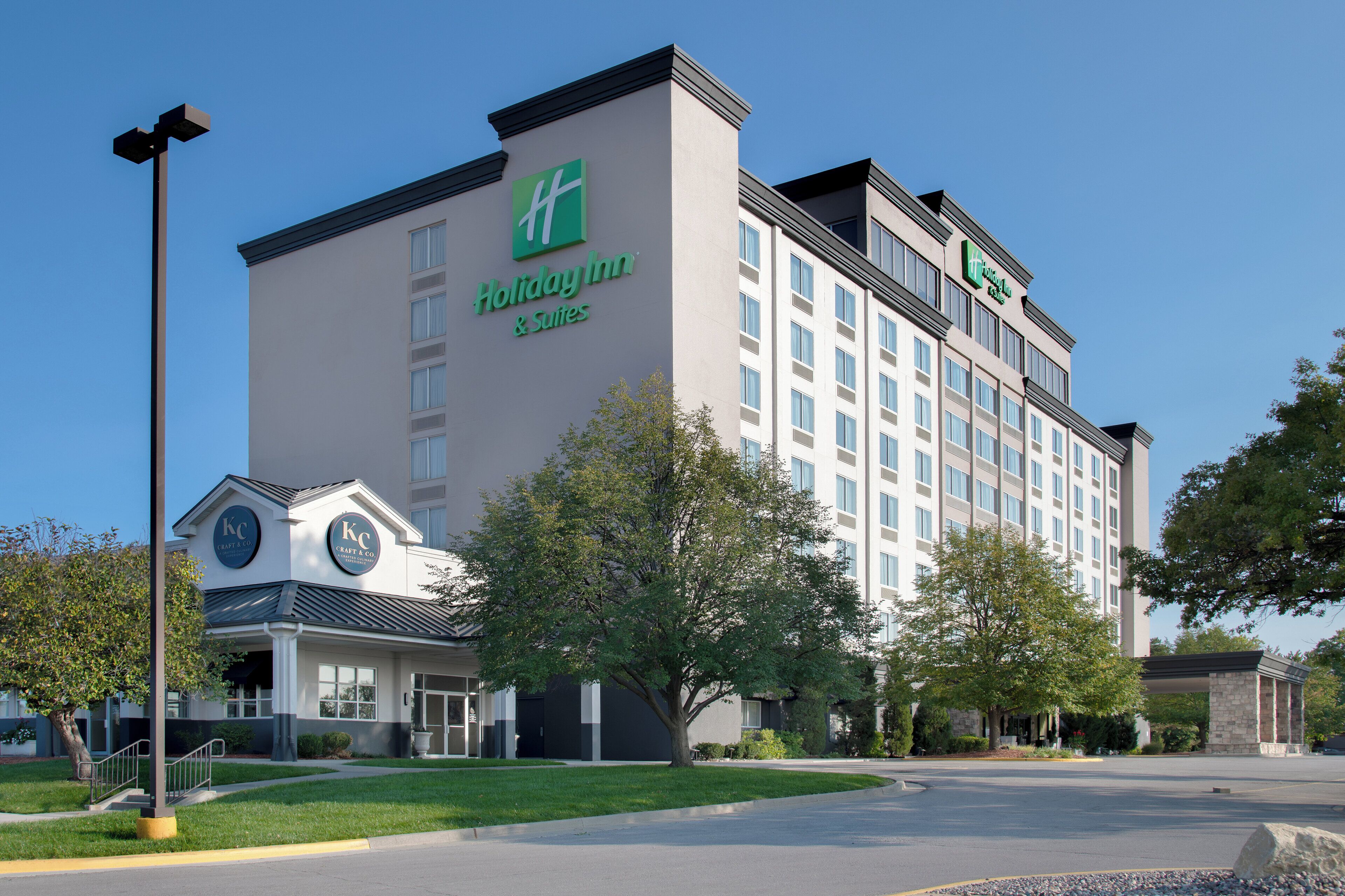 Ein Holiday Inn & Suites Hotel mit moderner Fassade, mehreren Etagen und einem Parkplatz vor dem Gebäude.