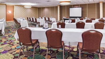 A conference room with multiple tables, chairs, and a projector screen.