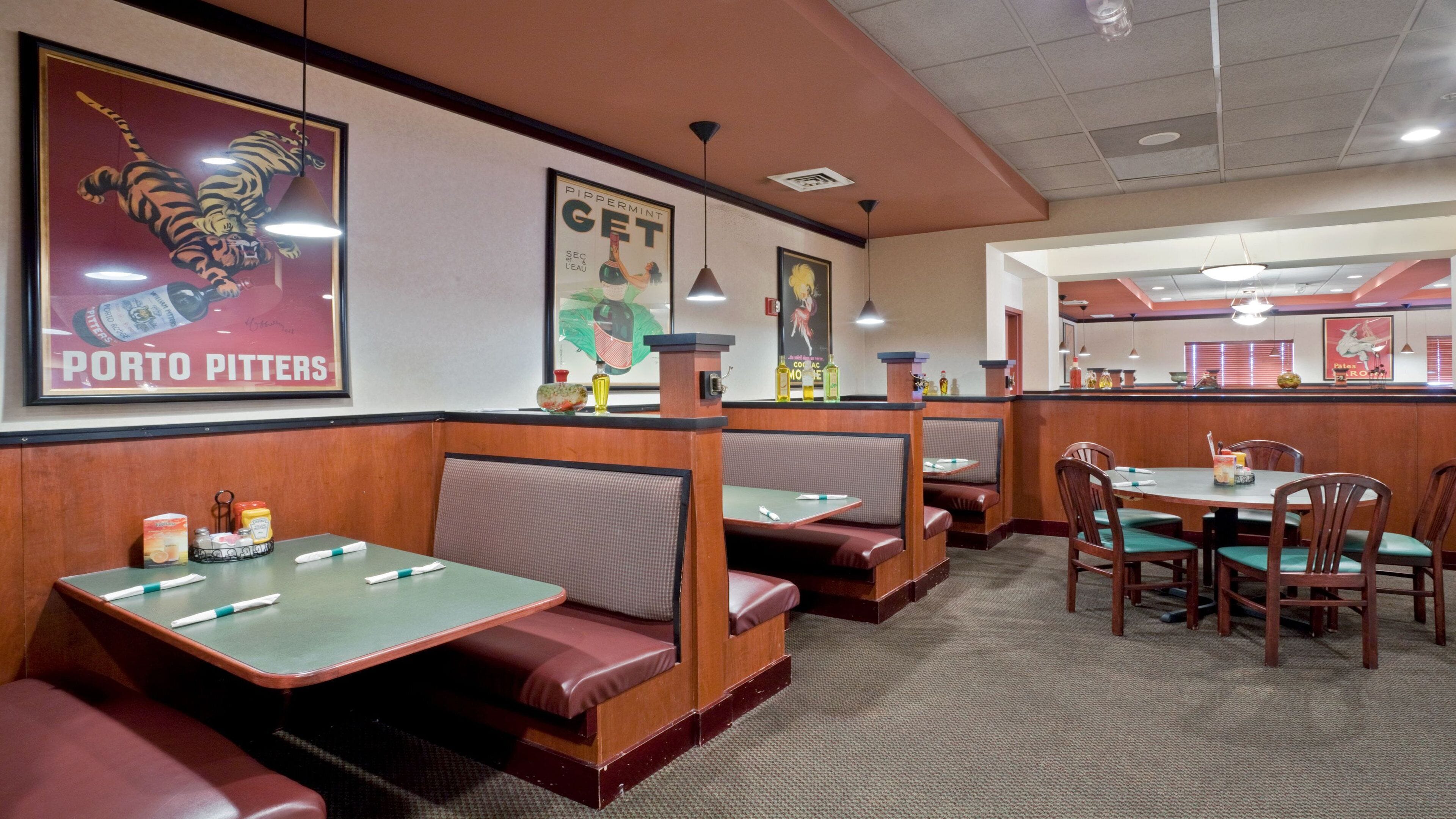 A restaurant interior with booths and tables, featuring posters on the walls and a counter area.