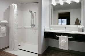 A modern bathroom with a walk-in shower, a large mirror, and a vanity with a towel rack. - Holiday Inn & Suites Overland Park West by IHG (Lenexa)