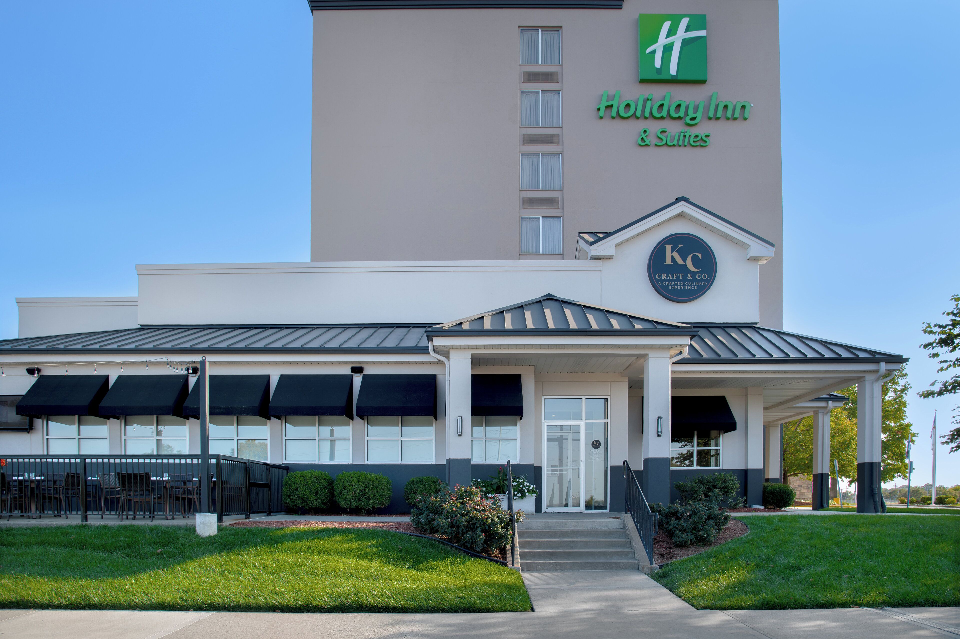 Edificio de Holiday Inn & Suites con un letrero de Crafts & Co., que presenta una fachada moderna, ventanas grandes y una entrada cubierta.