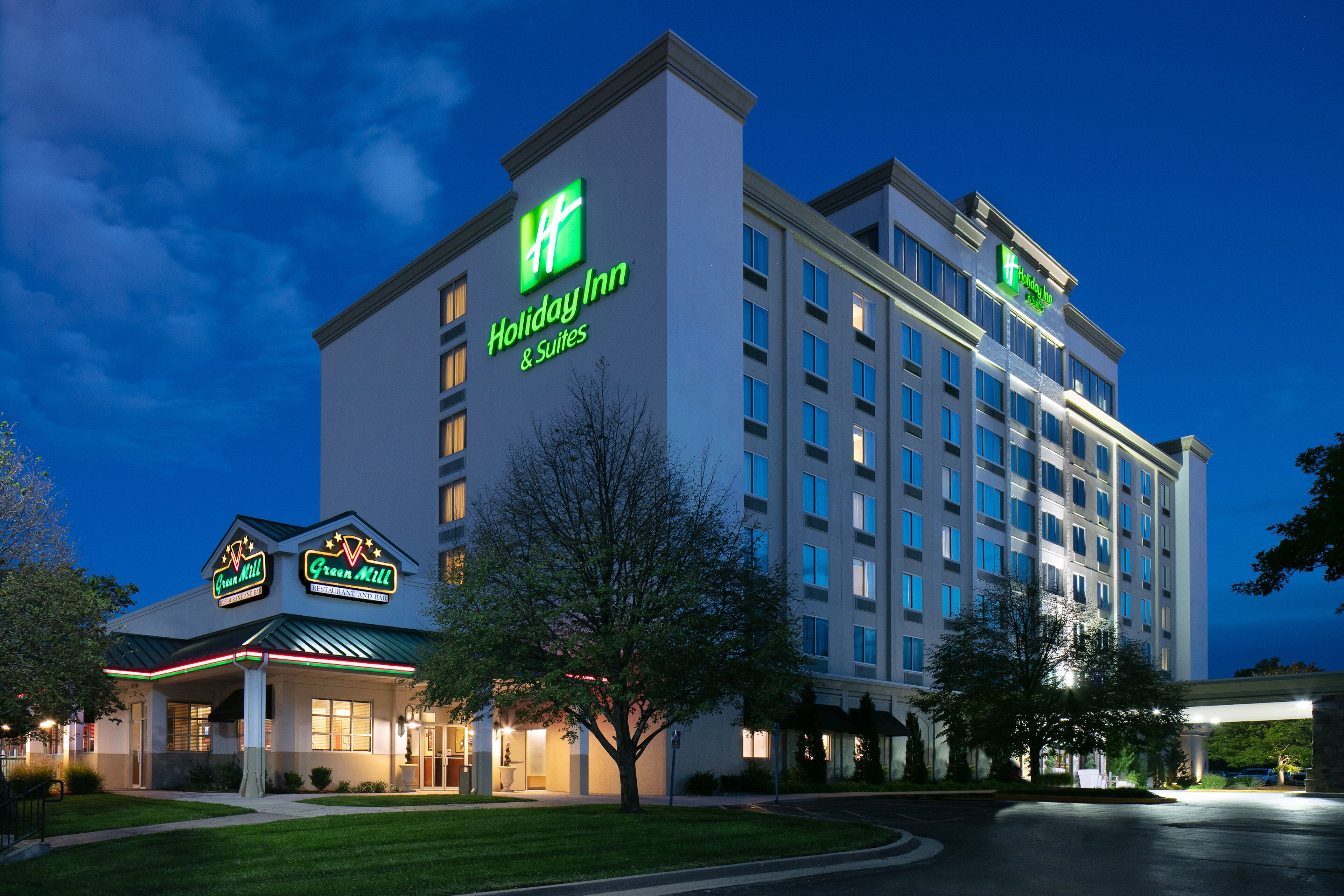 Un hôtel Holiday Inn au design moderne, avec un logo vert bien visible et une signalétique pour Holiday Inn & Suites.