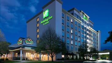 A Holiday Inn hotel with a modern design, featuring a prominent green logo and signage for the Holiday Inn & Suites.