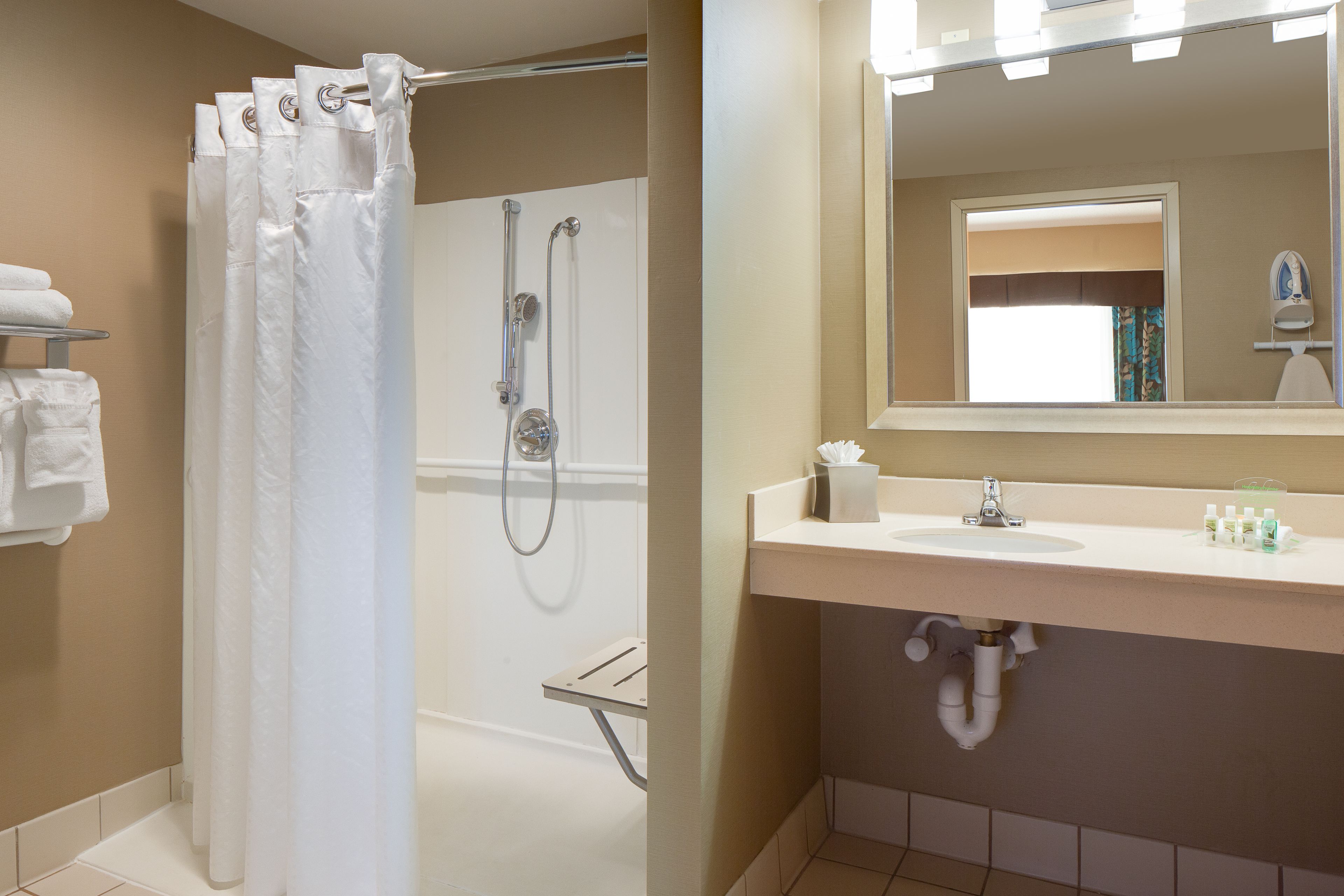 A bathroom with a shower, a sink, and a mirror.