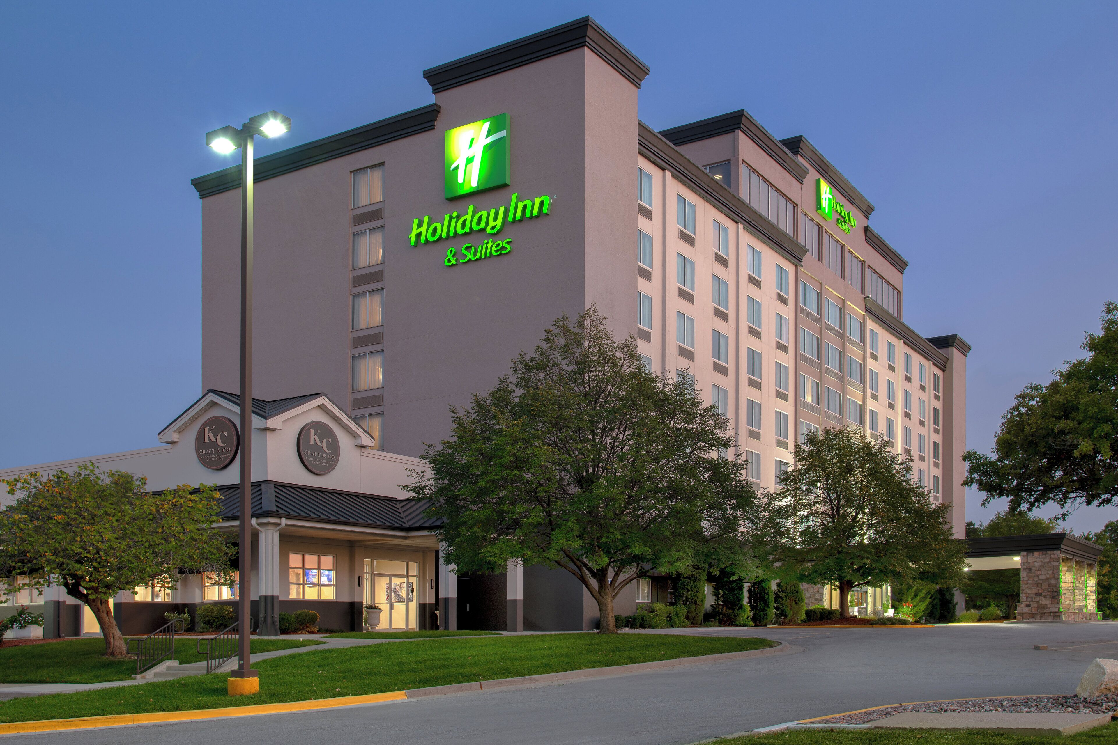 Un hotel Holiday Inn con fachada moderna, varios pisos y una entrada bien iluminada.