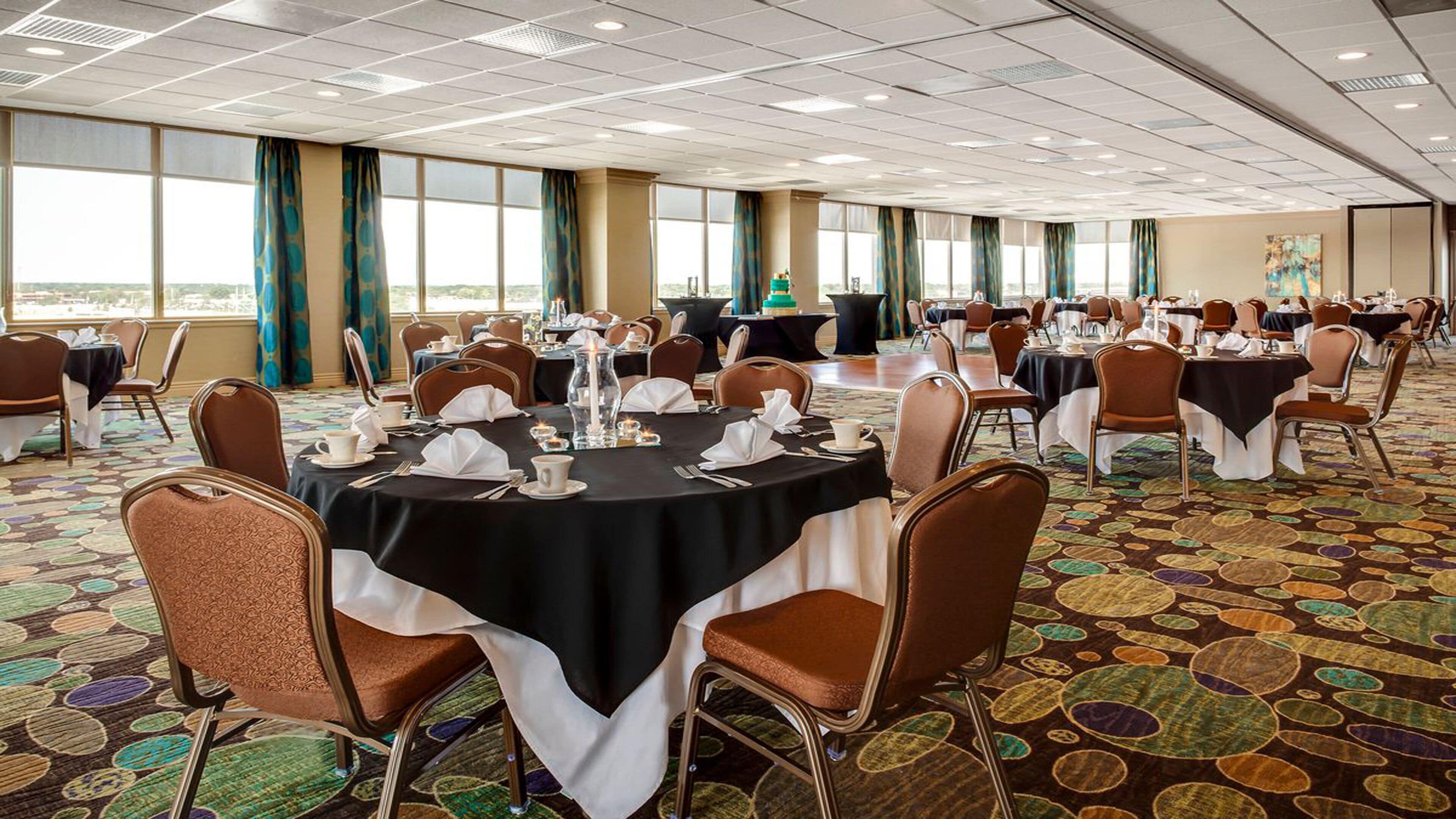 A conference room with round tables, chairs, and a carpeted floor.