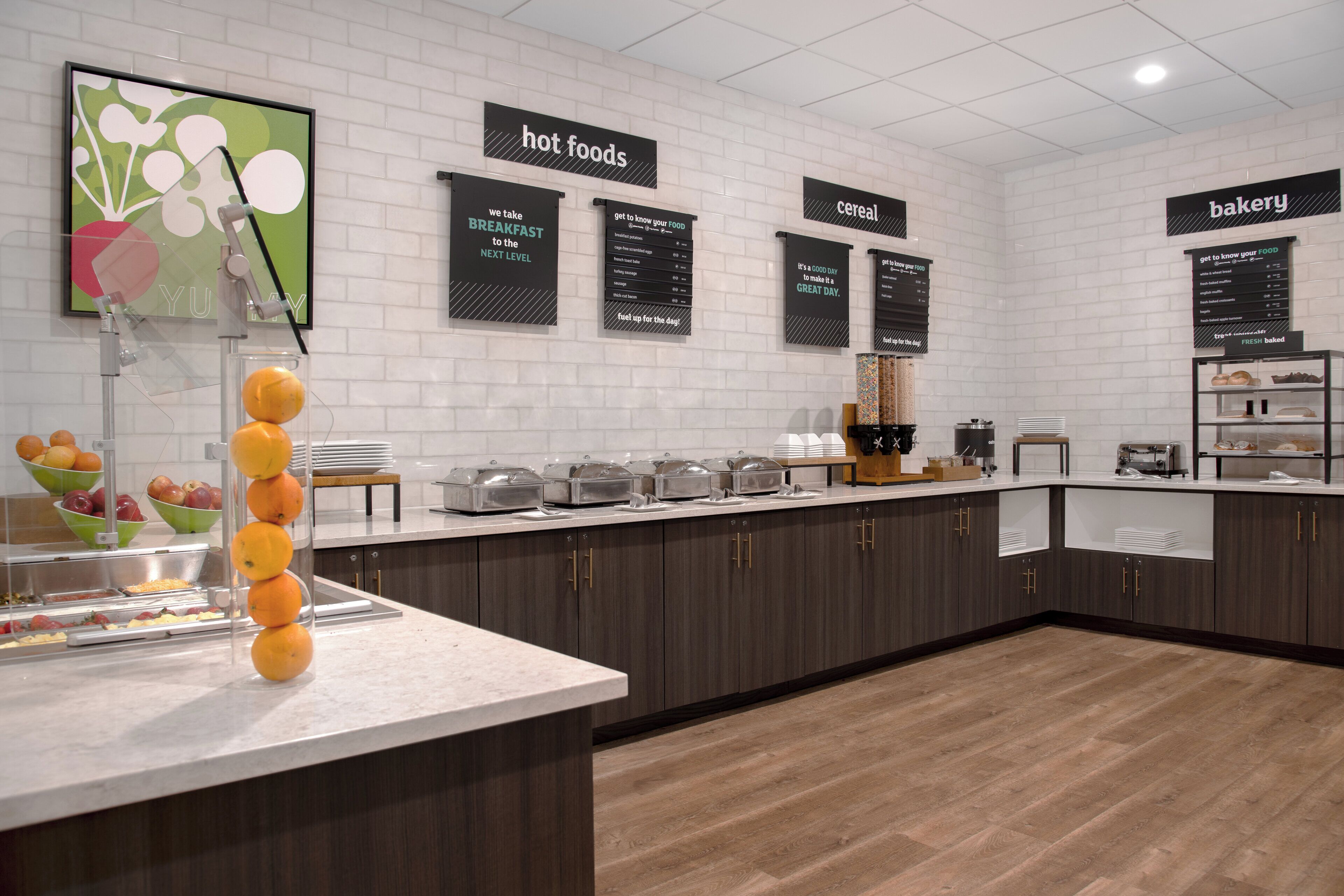Un buffet pour le petit-déjeuner, avec des présentoirs étiquetés pour les plats chauds, les céréales et les produits de boulangerie.