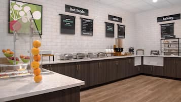 Un buffet pour le petit-déjeuner, avec des présentoirs étiquetés pour les plats chauds, les céréales et les produits de boulangerie.