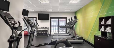 Un gimnasio con cintas de correr, elípticas y mancuernas.
