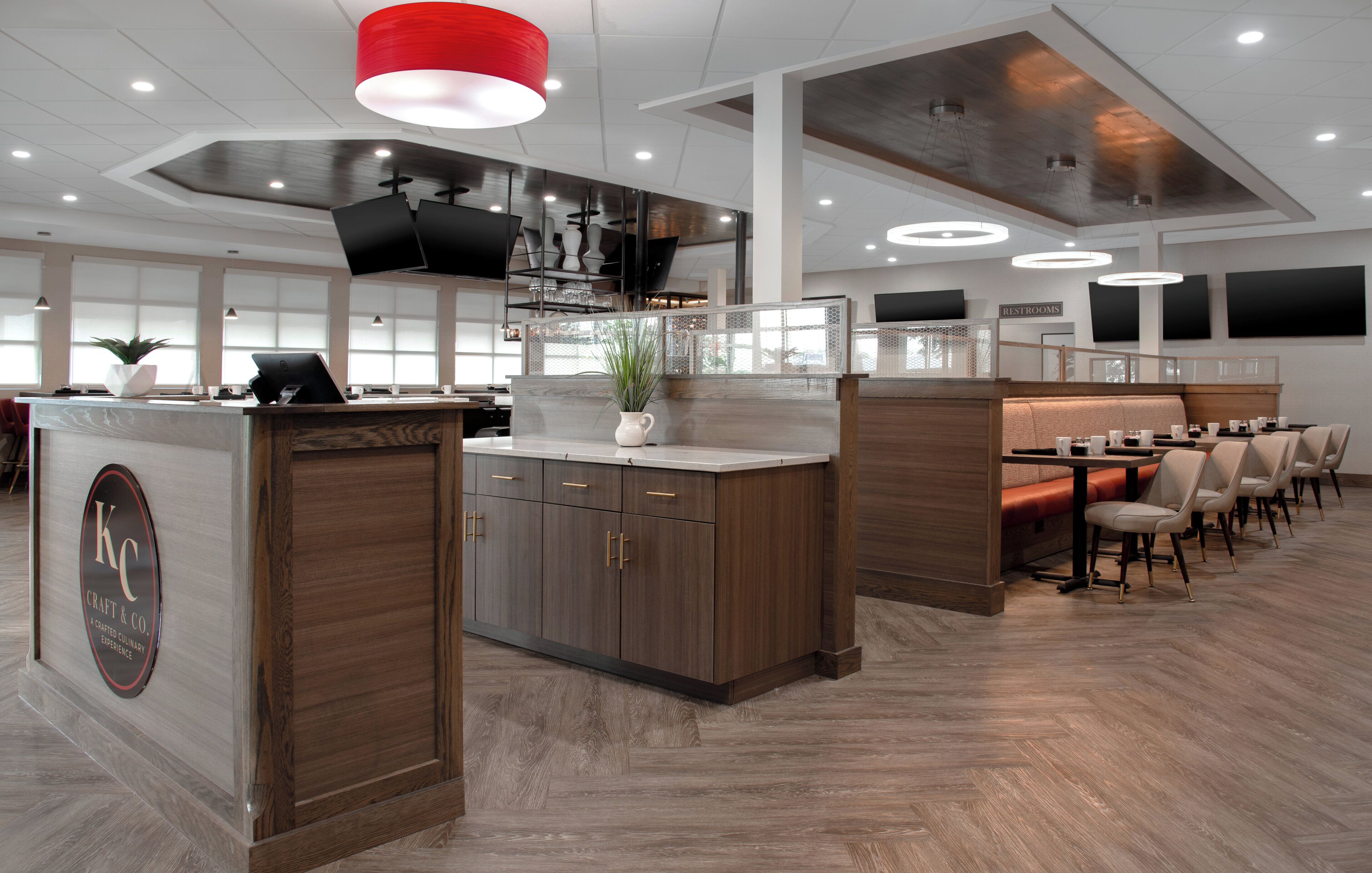 Un restaurante moderno con una isla central, muebles de madera y una zona de estar con mesas y sillas.