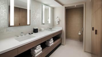 A modern bathroom with a large mirror, two sinks, and a wooden vanity.