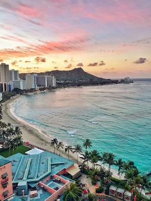 Un paisaje urbano costero con playa, edificios y una montaña al fondo.