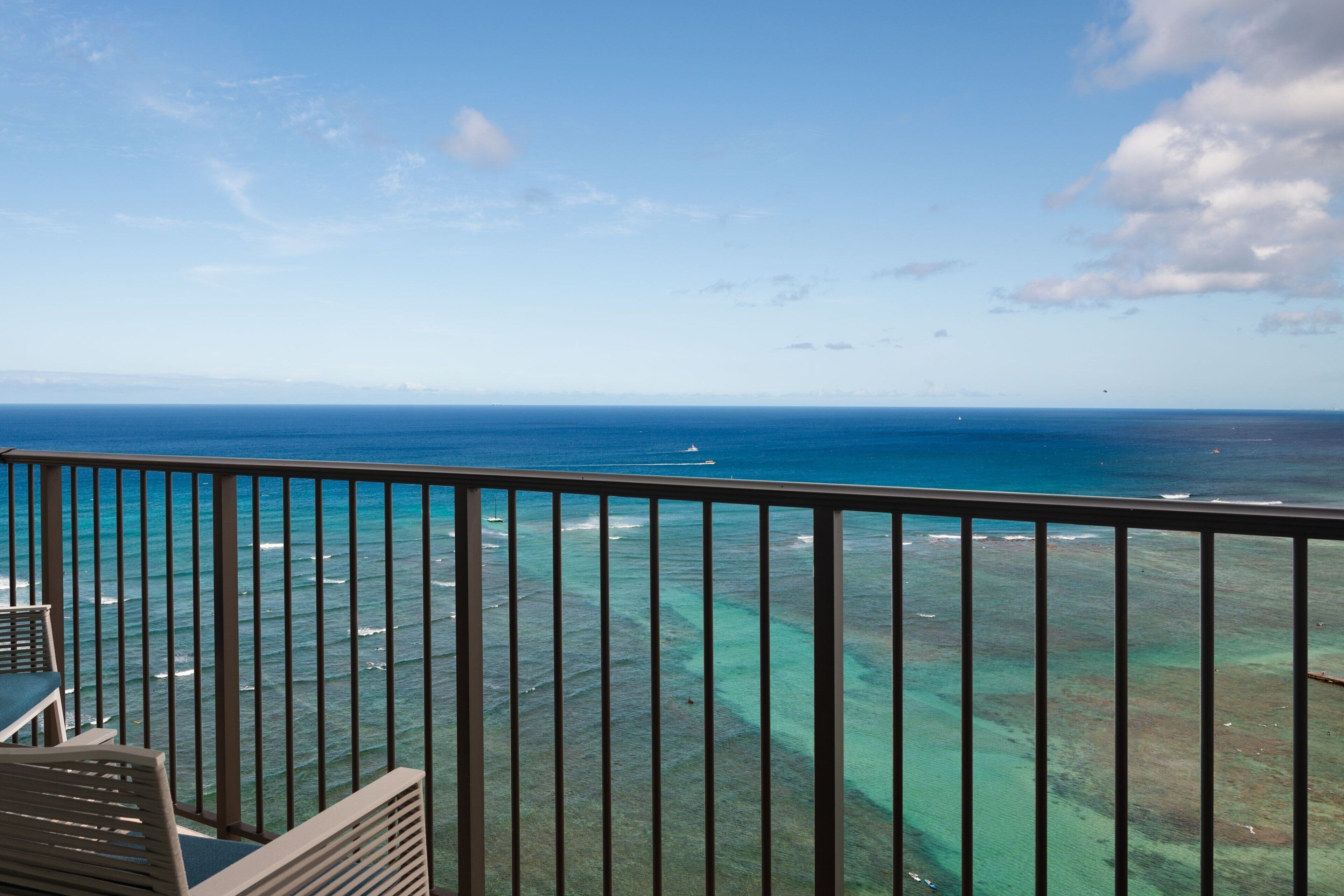 Un balcon avec vue sur l’océan et un ciel d’un bleu limpide.