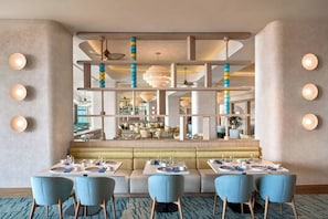 Un espace de restauration moderne avec un aménagement central des sièges, un éclairage au plafond et une vue sur une salle à manger.