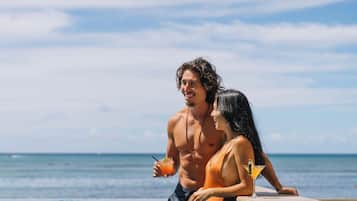 A couple by a pool with a view of the ocean.