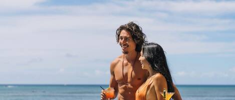A couple by a pool with a view of the ocean.