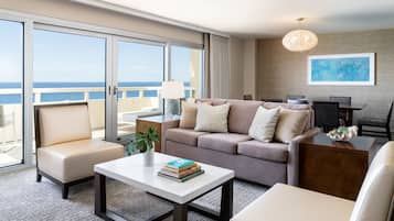 A modern hotel room with a balcony, a sofa, a coffee table, and a dining area.