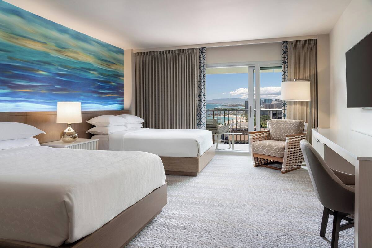 A hotel room with two beds, a desk, a chair, a balcony with a view of the city, and a painting on the wall.
