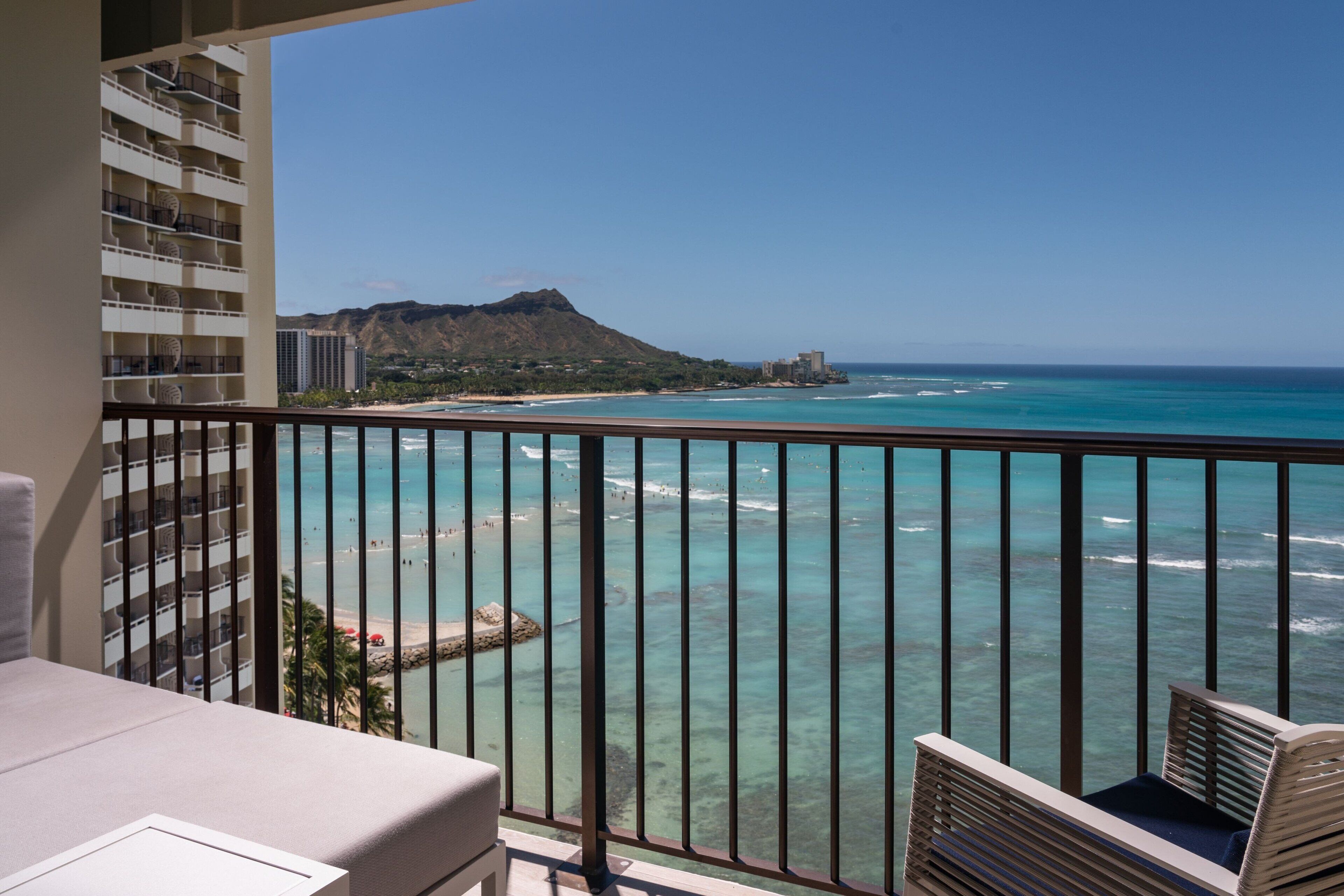 A balcony with a view of the ocean and a mountain.