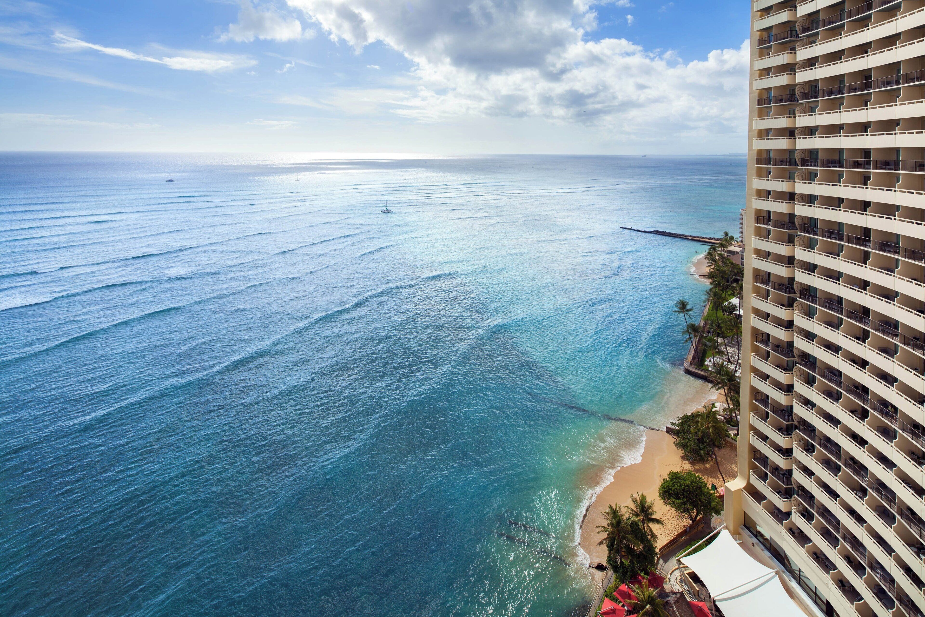 Un hotel di grandi dimensioni con vista su una spiaggia, acque blu cristalline e una riva sabbiosa.