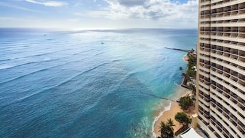 Un hotel di grandi dimensioni con vista su una spiaggia, acque blu cristalline e una riva sabbiosa.