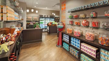 Una tienda de dulces con estantes llenos de golosinas variadas, una sección refrigerada y un área de regalos.