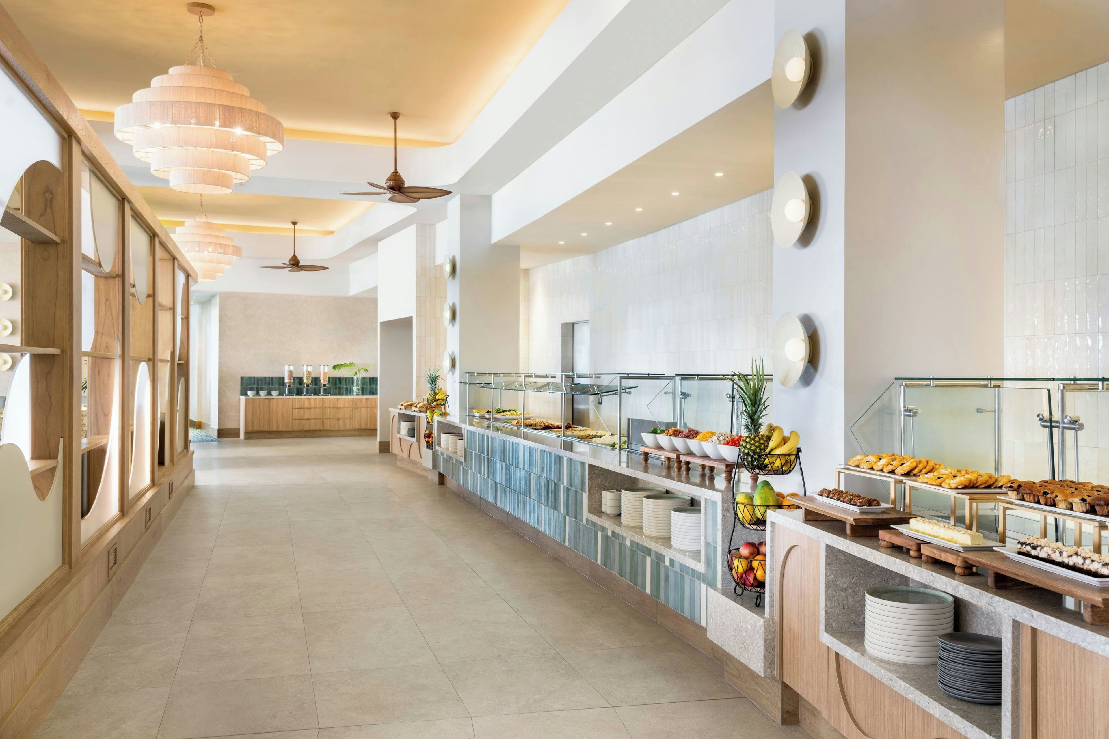 A buffet area with multiple food stations, a long counter, and ceiling fans.