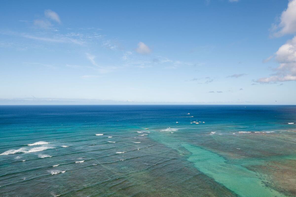 Vista aérea de una zona costera con aguas azul turquesa y una línea de costa visible.