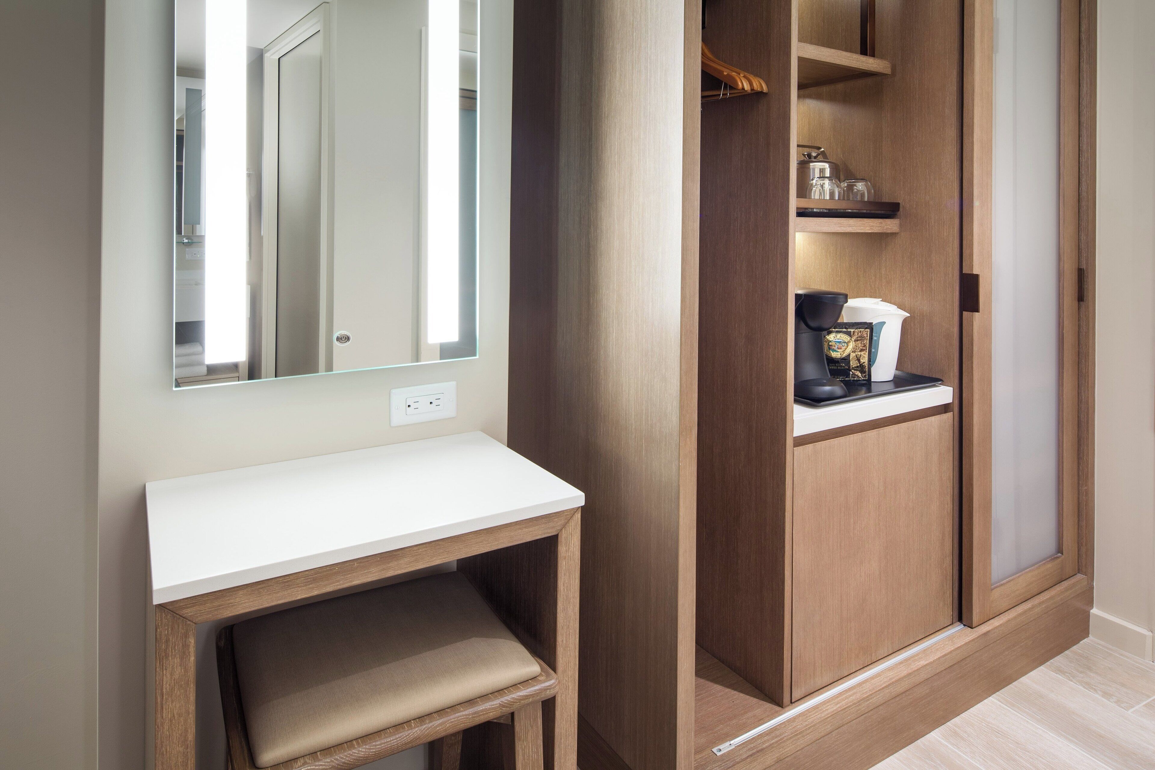 A bathroom with a mirror, a vanity, and a wooden cabinet with shelves.