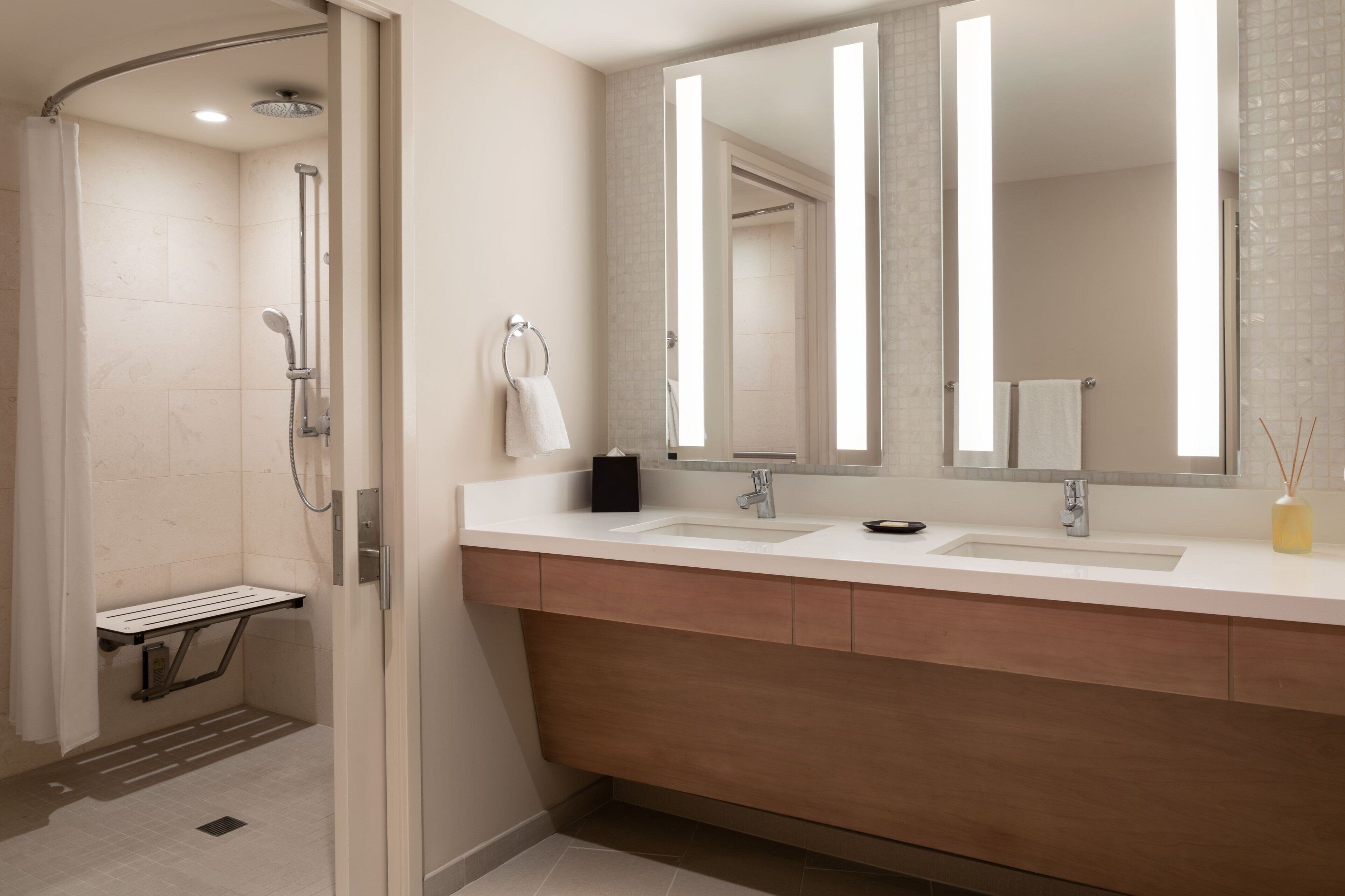 Une salle de bain moderne avec une douche, deux lavabos et un grand miroir.