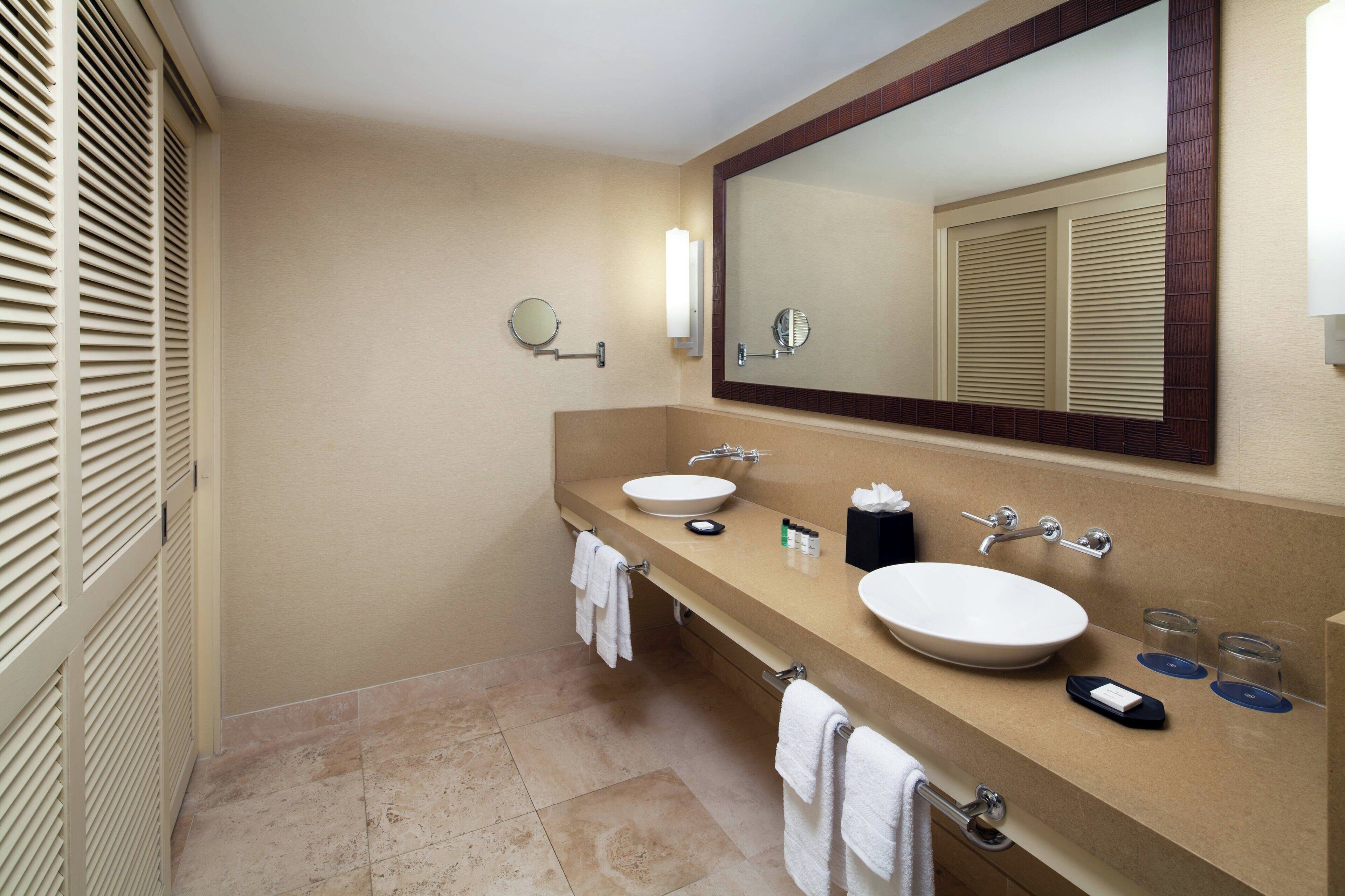 A bathroom with two sinks, a large mirror, and a towel rack.