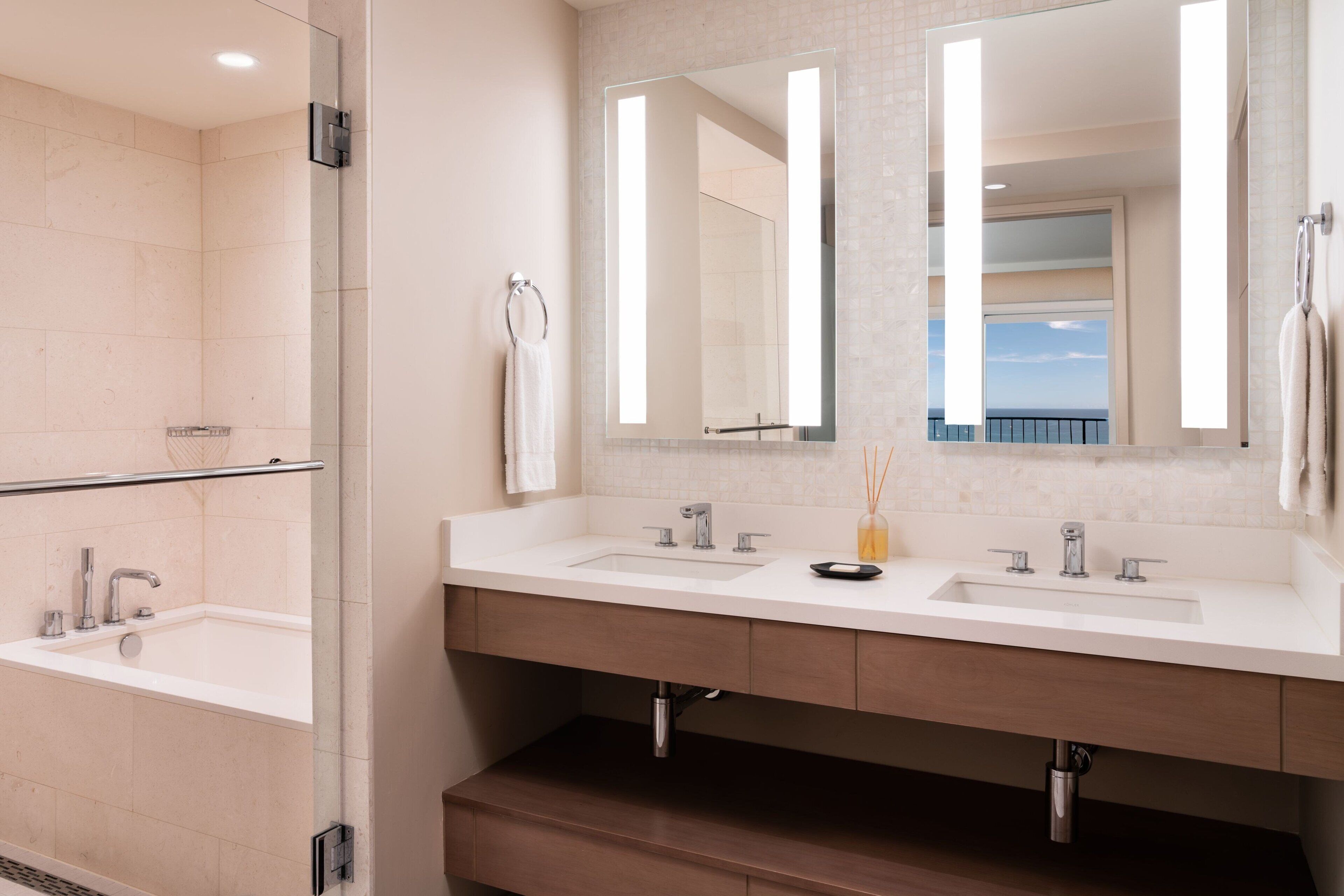 Une salle de bain moderne avec deux lavabos, un grand miroir et une douche à l’italienne.