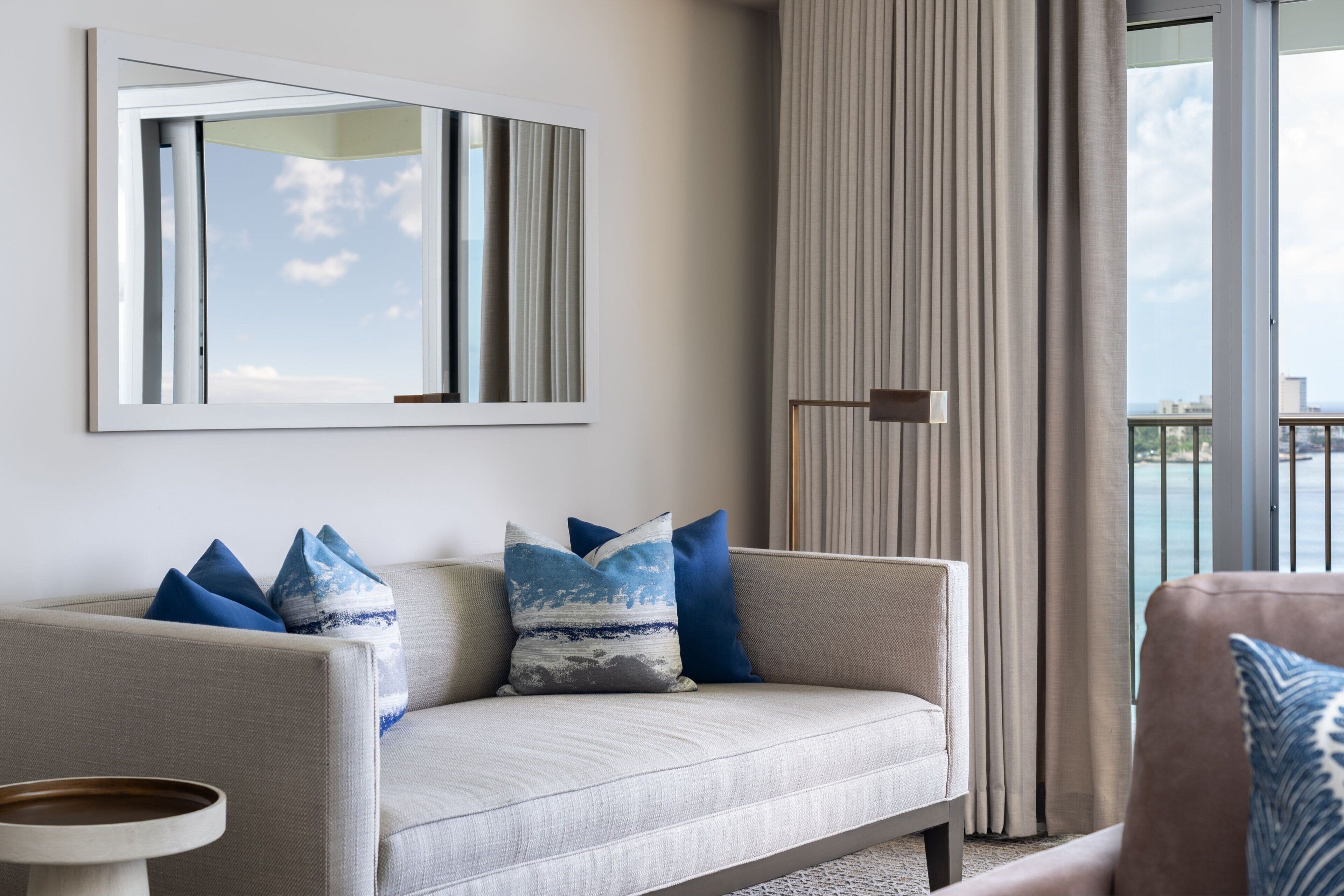 Una sala de estar moderna con un sofá, una mesa de centro y un ventanal con cortinas.