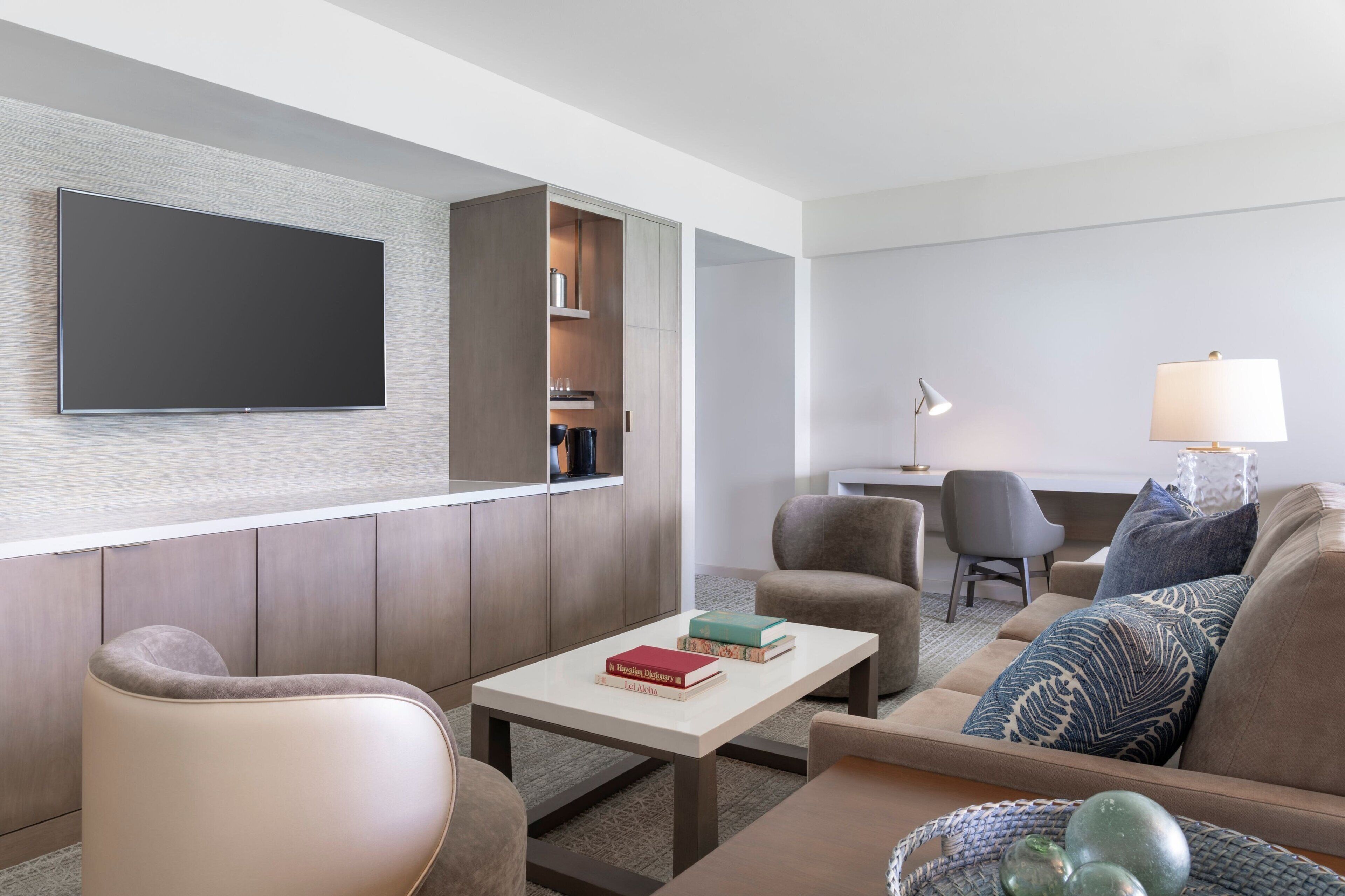 A modern living room with a flat-screen TV, a sofa, a coffee table, and a lamp.