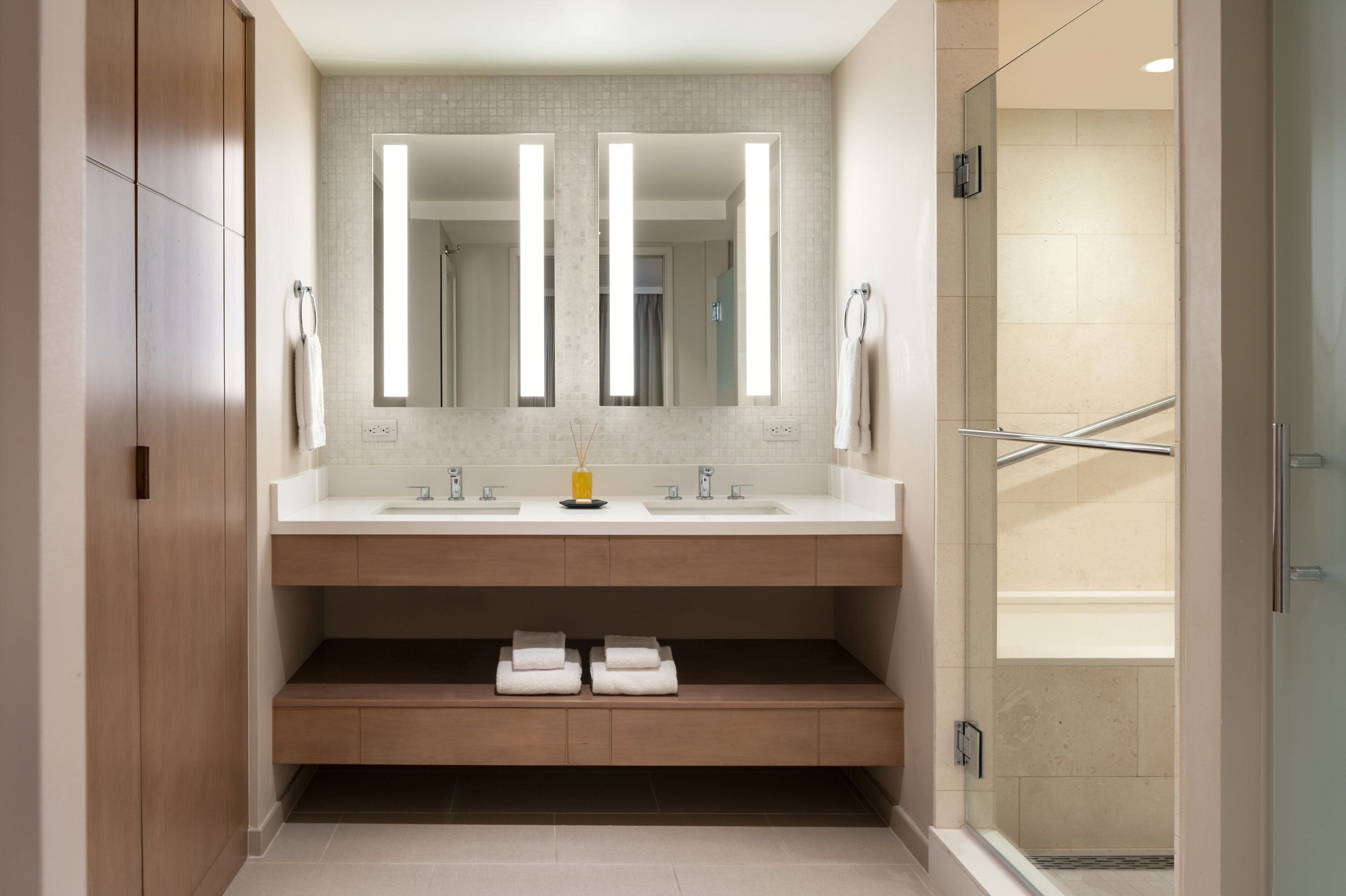 Un bagno moderno con due lavabi, un ampio specchio e una zona doccia.