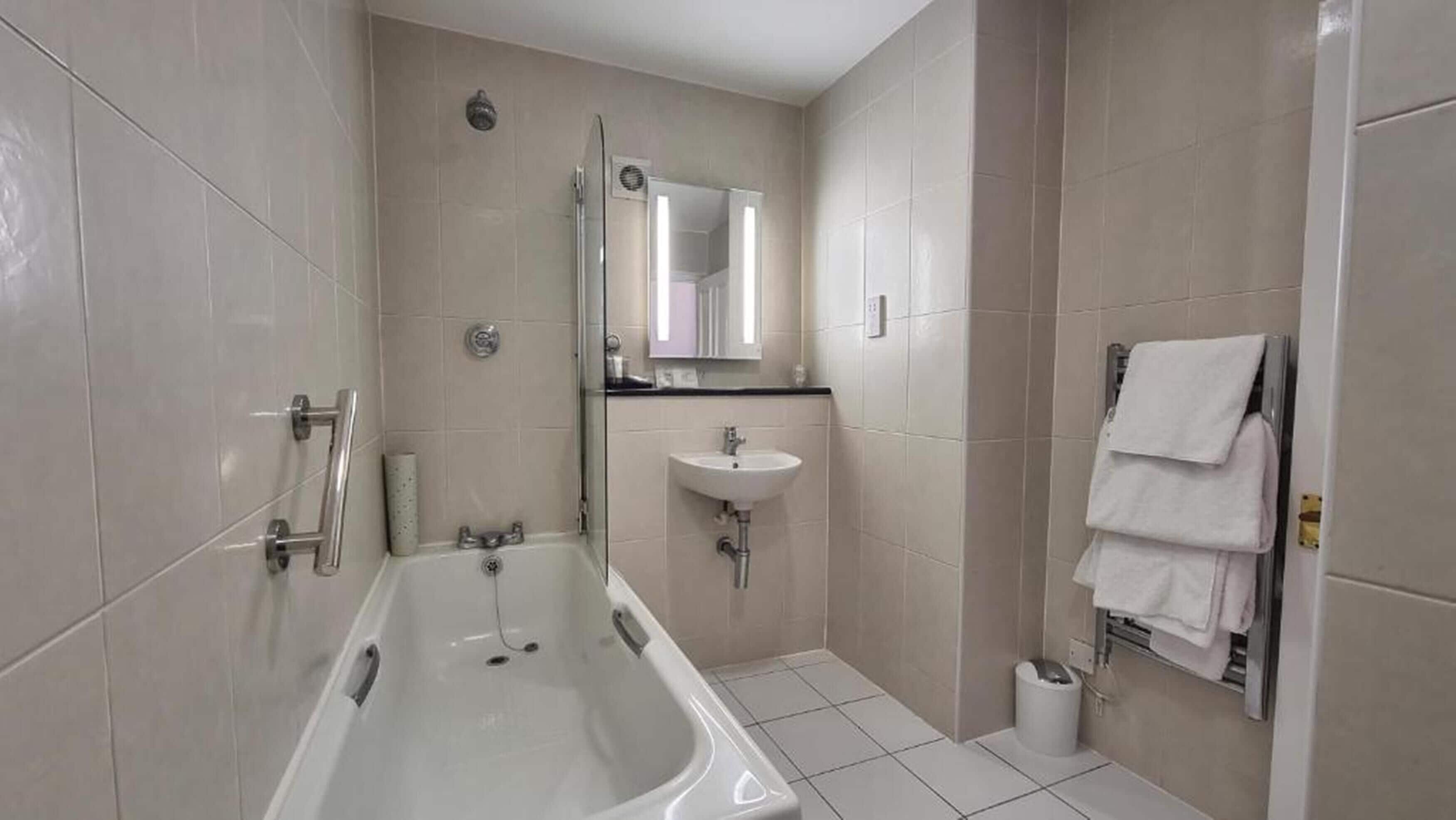 Un baño moderno con bañera, lavamanos y espejo.