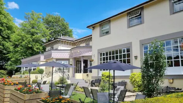 A hotel with a patio area featuring outdoor seating and planters with flowers. - Reigate Manor (Reigate)