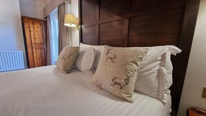A neatly made bed with white linens and decorative pillows featuring animal prints. - Reigate Manor (Reigate)