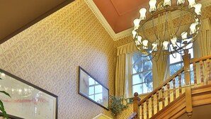 A grand staircase with ornate woodwork and a patterned carpet leading to a room labeled "The Garden Room". - Reigate Manor (Reigate)